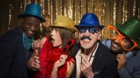 Friends taking photobooth selfies at a lively event, capturing joyful expressions and playful poses in a casual setting.