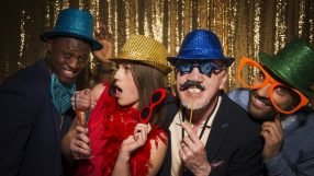 Friends taking photobooth selfies at a lively event, capturing joyful expressions and playful poses in a casual setting.