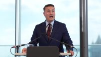 Wes Streeting, British politician, delivering a speech at a press conference with a focused expression and engaging the au...