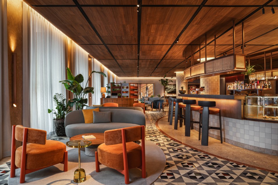 Stylish interior of a modern caf&eacute; featuring colorful furniture, a well-lit bar area, and decorative plants.