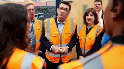 Andy Burnham in a hi-vis vest, with other officials, during a visit to a facility.