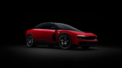 Red Ferrari Luce concept car with black roof and wheels, yellow brake calipers, against a dark background.