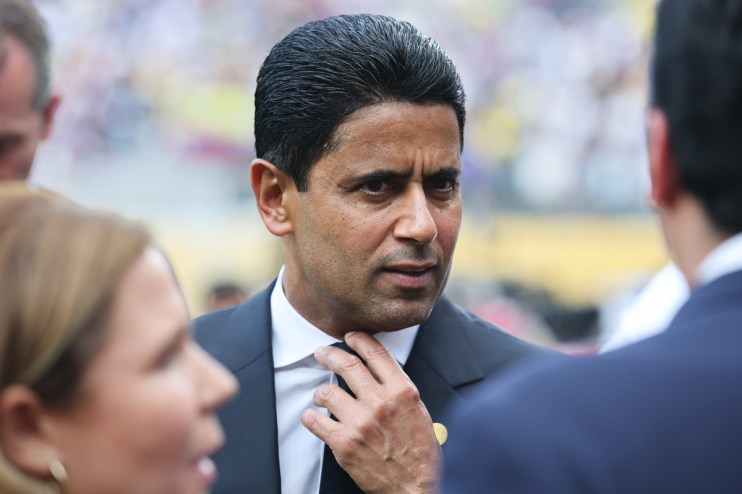 Nasser Al-Khelaifi adjusting his tie, speaking to another person in a business setting