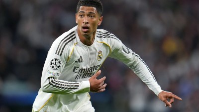Jude Bellingham in a white Real Madrid jersey with black stripes, looking focused on the field during a match.