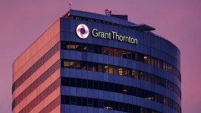 Grant Thornton building exterior with illuminated logo and name against a dramatic pink and purple sky at dusk.