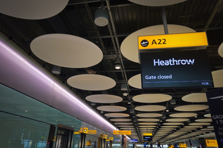 Heathrow airport terminal with Gate closed flight information display and modern ceiling design, highlighting infrastructure.