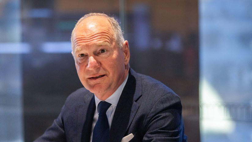 Heathrow CEO Thomas Woldbye in a dark suit and tie, looking forward with a serious expression in an office setting.