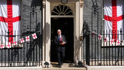 Keir Starmer exiting a building, dressed in a suit, amid media attention, reflecting leadership and political significance