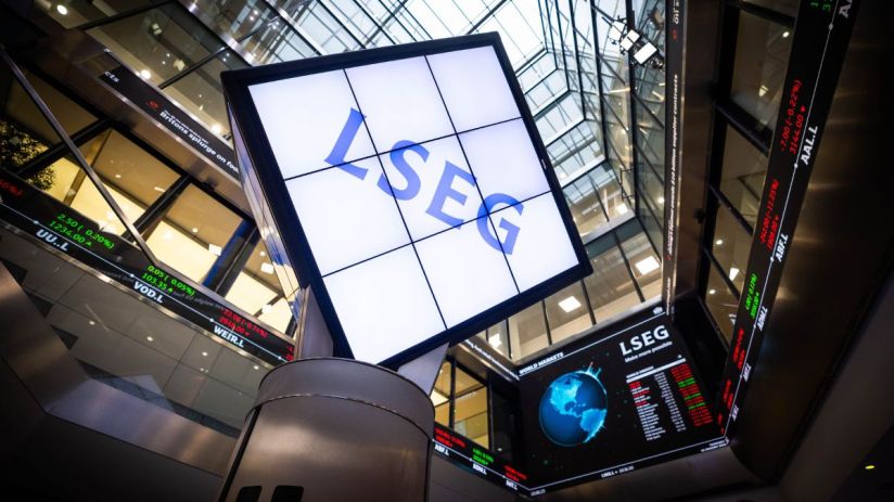 LSEG logo on a large screen inside a modern building with stock tickers and glass ceilings.