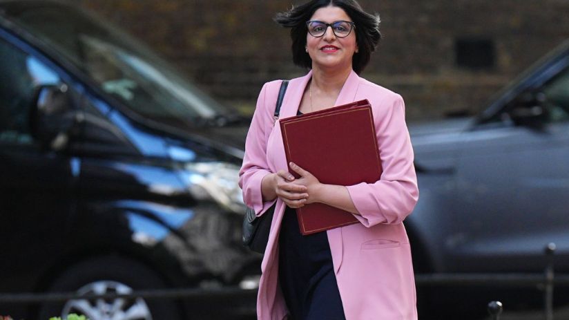 Shabana Mahmood speaking at a podium during a public event, wearing a formal suit, addressing an audience with confidence.