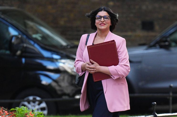 Shabana Mahmood speaking at a podium during a public event, wearing a formal suit, addressing an audience with confidence.