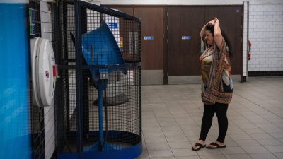 Crowded London Underground platform during summer heat wave, passengers fanning themselves to stay cool