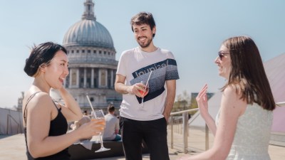 Three friends enjoying drinks on a rooftop bar with St Pauls Cathedral dome in the background.