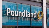 Poundland store sign with white letters and a yellow wreath logo, reflected in blue tinted windows
