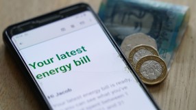 Smartphone displaying an energy bill, with British pounds and coins beside it, symbolizing rising costs.