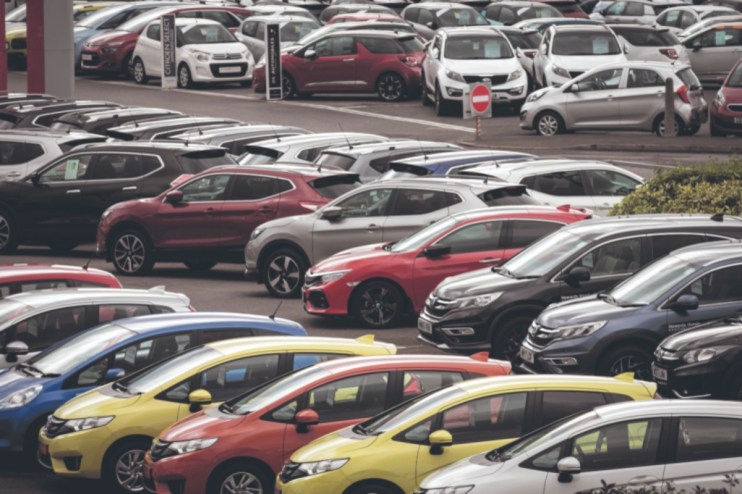 Rows of new and used cars parked at a dealership lot, ready for sale.