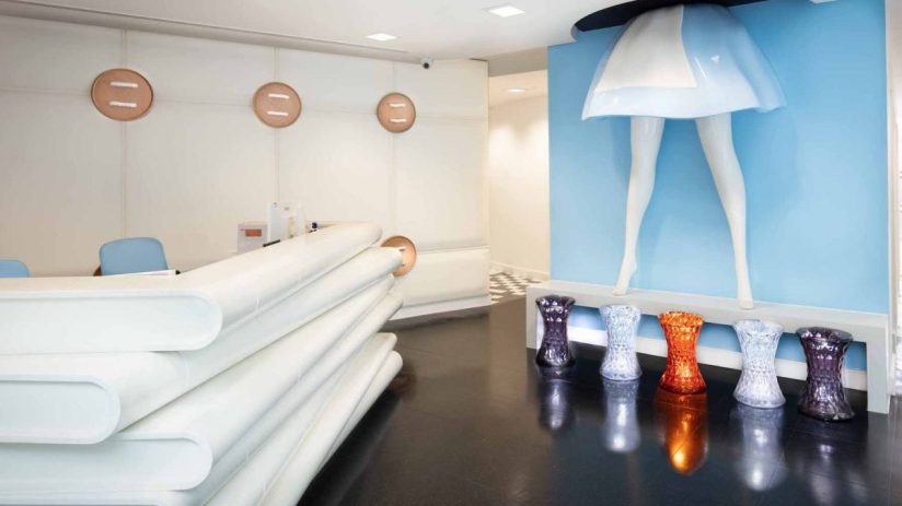 Modern reception area with unique legs art installation, white desk, and colorful stools.