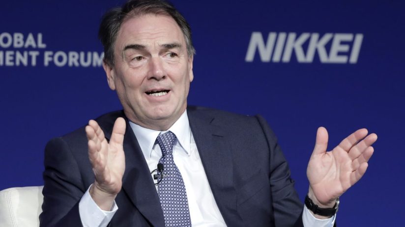 Alan Parker speaking at a business forum, gesturing with hands, blue background with NIKKEI and FORUM visible