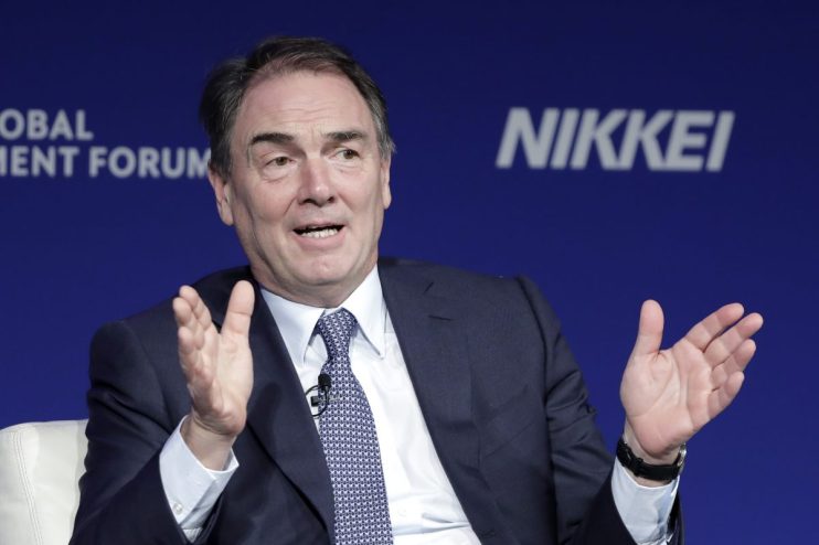 Alan Parker speaking at a business forum, gesturing with hands, blue background with NIKKEI and FORUM visible