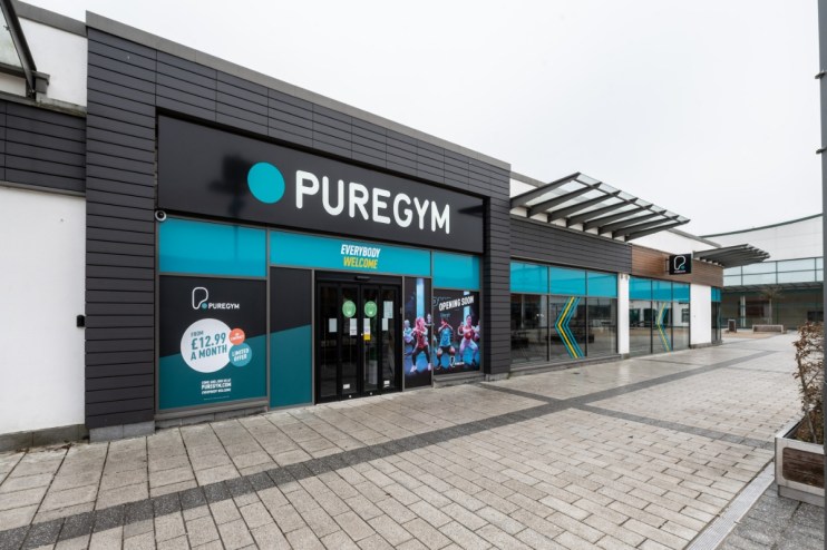 Exterior view of PureGym Aldershot, a modern fitness center with large windows and promotional signage