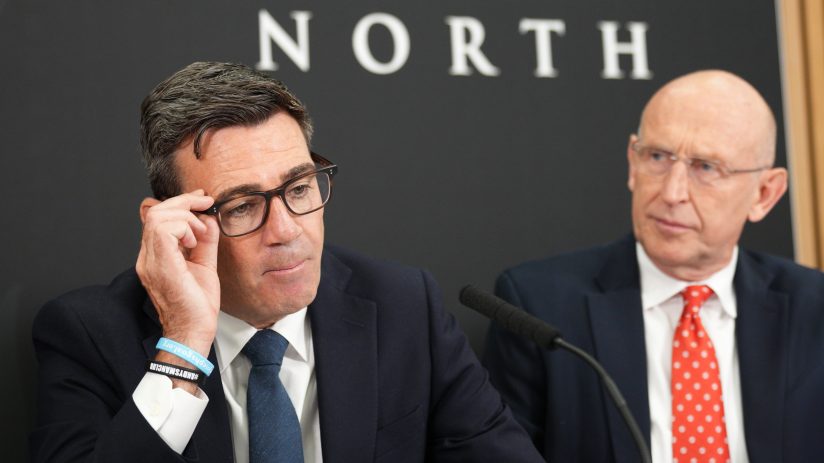 Andy Burnham and John Healey at Number 10 North, both wearing suits and ties, with a microphone in the foreground.