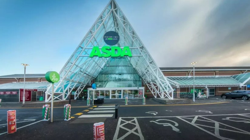 External view of a modern Asda supermarket entrance with a prominent green logo and glass pyramid-like structure.