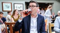 Andy Burnham in glasses drinking a pint of beer at a pub gathering.