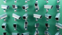 Multiple CCTV security cameras in light blue and white against a green background, emphasizing surveillance and monitoring.