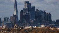 London skyline with The Shard, Walkie Talkie, and Gherkin skyscrapers towering over residential buildings and autumn trees.