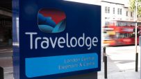 Travelodge London Central Elephant & Castle sign with a blurred red double-decker bus in the background
