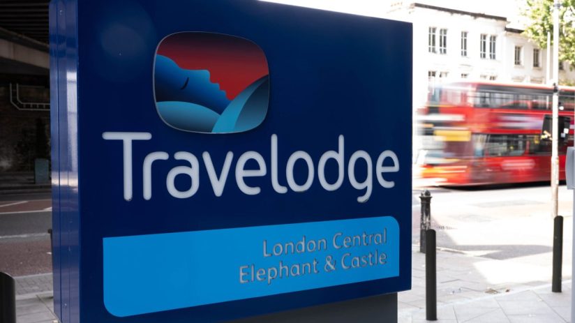 Travelodge London Central Elephant & Castle sign with a blurred red double-decker bus in the background