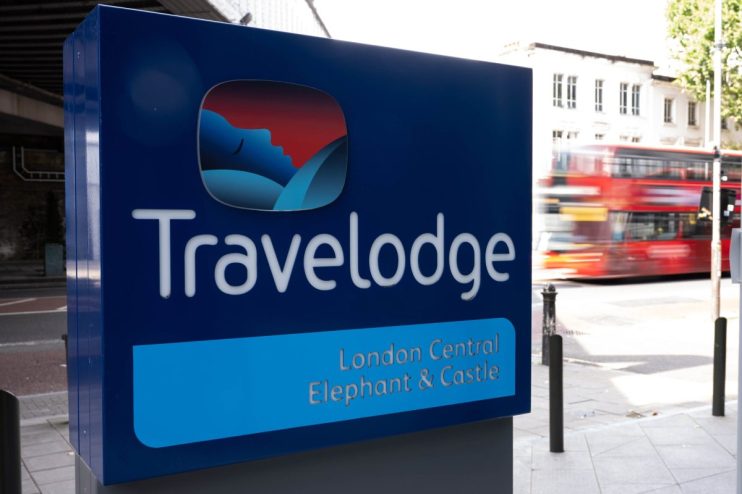 Travelodge London Central Elephant & Castle sign with a blurred red double-decker bus in the background