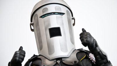 Count Binface in his distinctive silver bin helmet and black armored suit, giving two thumbs up.