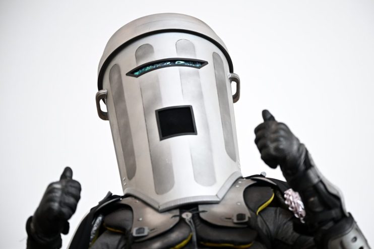 Count Binface in his distinctive silver bin helmet and black armored suit, giving two thumbs up.