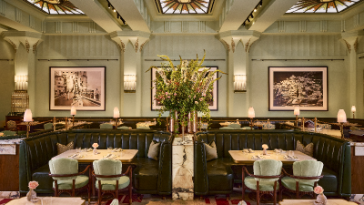 Elegant Dante Mayfair dining room with green booths, marble tables, floral centerpiece, and stained glass ceiling.