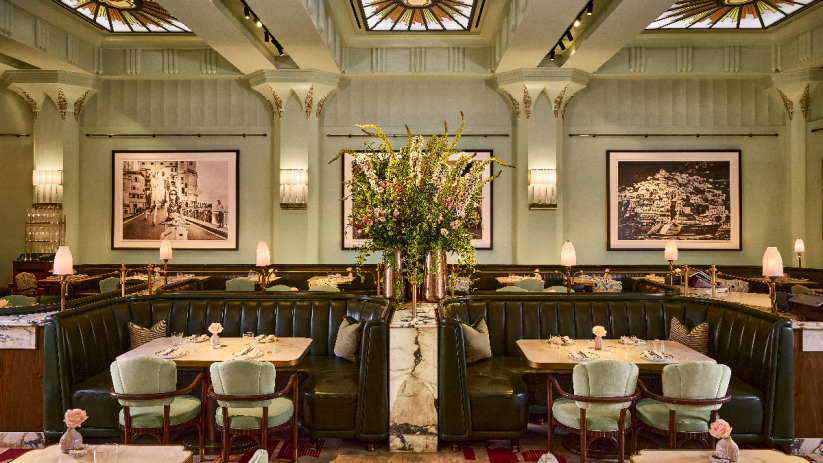 Elegant Dante Mayfair dining room with green booths, marble tables, floral centerpiece, and stained glass ceiling.