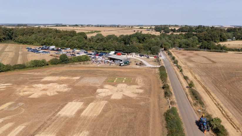 Aerial view of dry, brown farm fields affected by high temperatures, with a road and farm buildings.