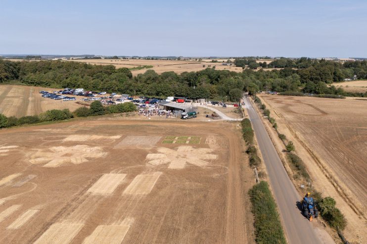 Aerial view of dry, brown farm fields affected by high temperatures, with a road and farm buildings.