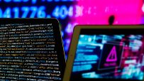 Two tablets displaying code and a cyber warning symbol, with blurry blue and pink background numbers