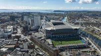 Aerial view of Cardiff city, Principality Stadium, and surrounding buildings under a blue sky