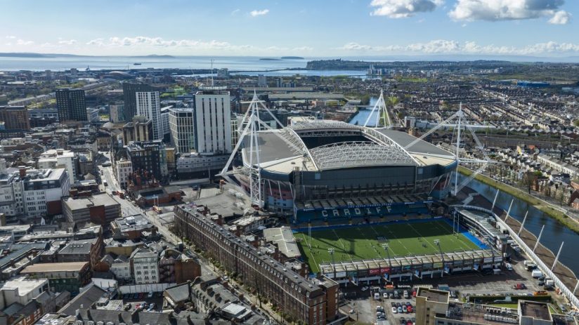 Aerial view of Cardiff city, Principality Stadium, and surrounding buildings under a blue sky