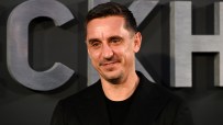Gary Neville, former footballer and businessman, smiling in a black suit against a dark background