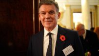 Sir Hugh Robertson, British Olympic Association, wearing a poppy and name tag, at an event