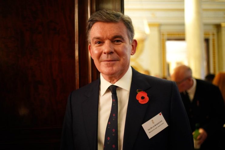 Sir Hugh Robertson, British Olympic Association, wearing a poppy and name tag, at an event