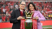 John W. Henry and Linda Pizzuti Henry with the Premier League trophy at a stadium.