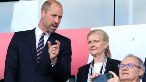 Prince William speaking with a woman and a man holding a phone at an event