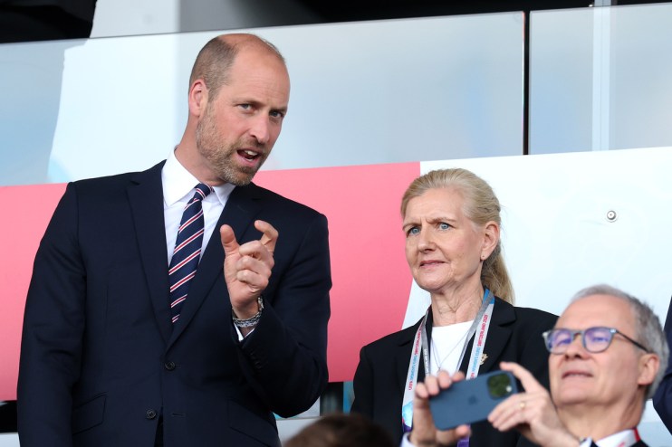 Prince William speaking with a woman and a man holding a phone at an event