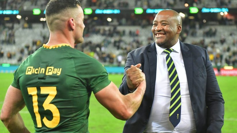 Rugby player in green jersey with Pic n Pay 13 shaking hands with a smiling man in a suit and tie