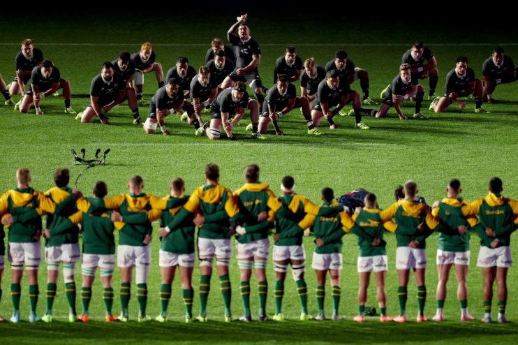 New Zealand All Blacks perform the Haka facing South African Springboks rugby team on field.