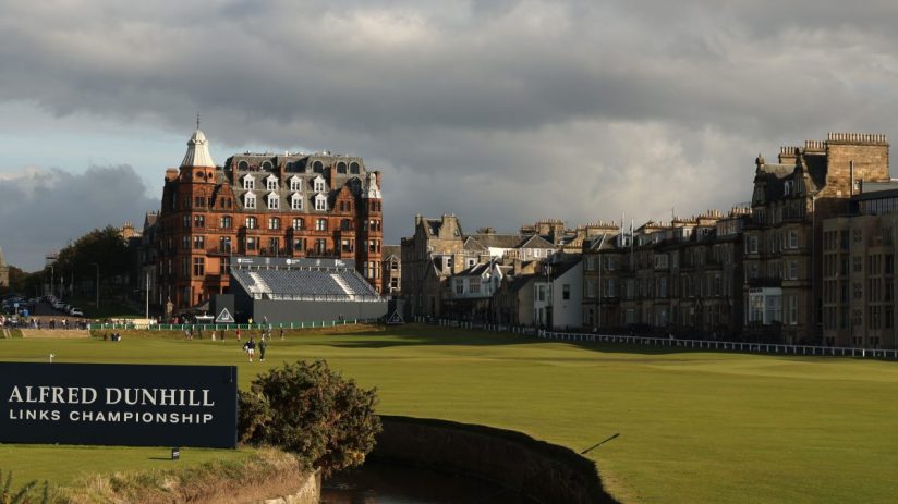 Golf course with the Old Course Hotel and town buildings in St Andrews, Scotland, under cloudy skies.